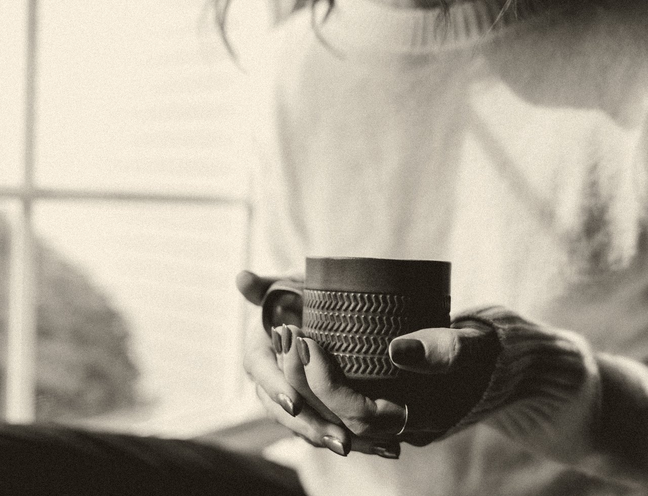 Hands cradling a warm ceramic cup in morning light
