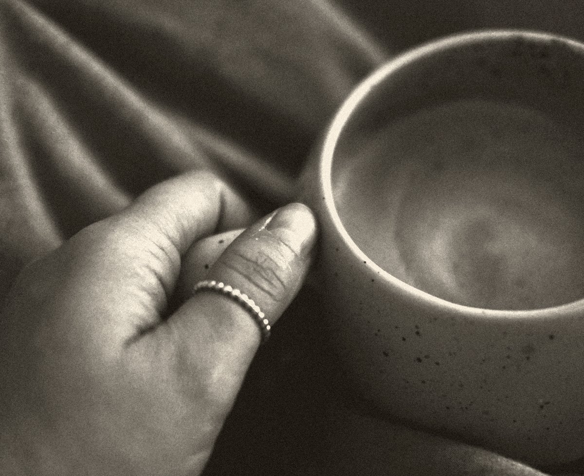 A hand resting on a warm ceramic cup